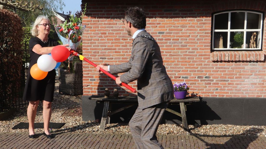 Met een beetje creativiteit weet burgemeester De Graaf toch een bos bloemen aan mevrouw Wierenga te geven.