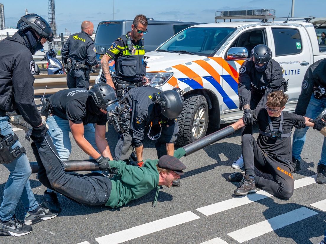 De politie moest de demonstranten losmaken van de weg en ze daarna weghalen.