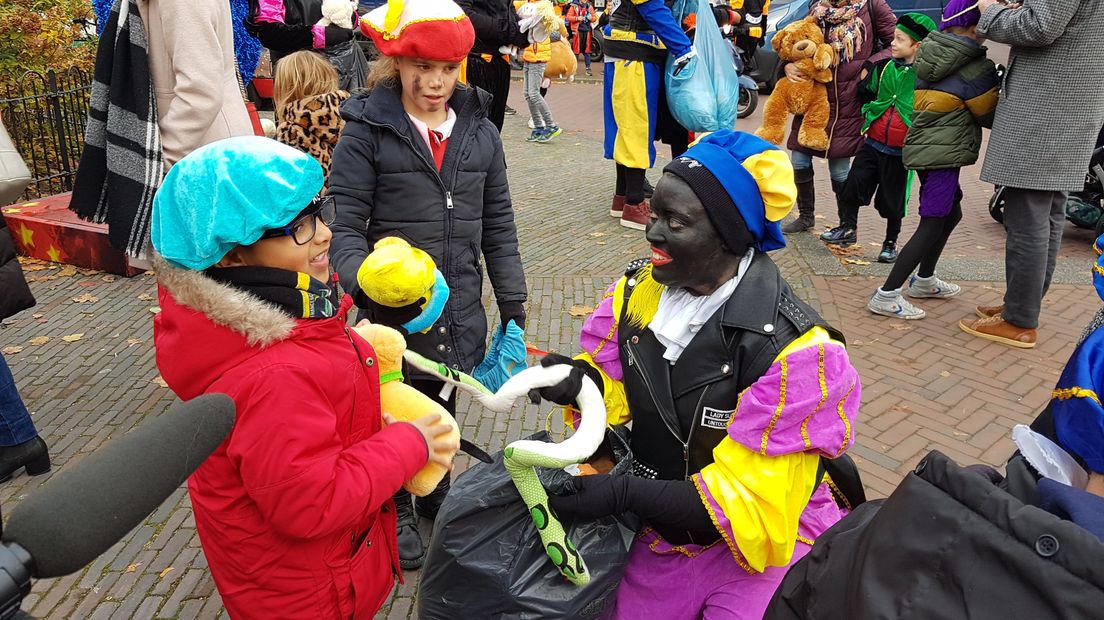 Zwarte Pieten delen knuffels uit tijdens optocht.