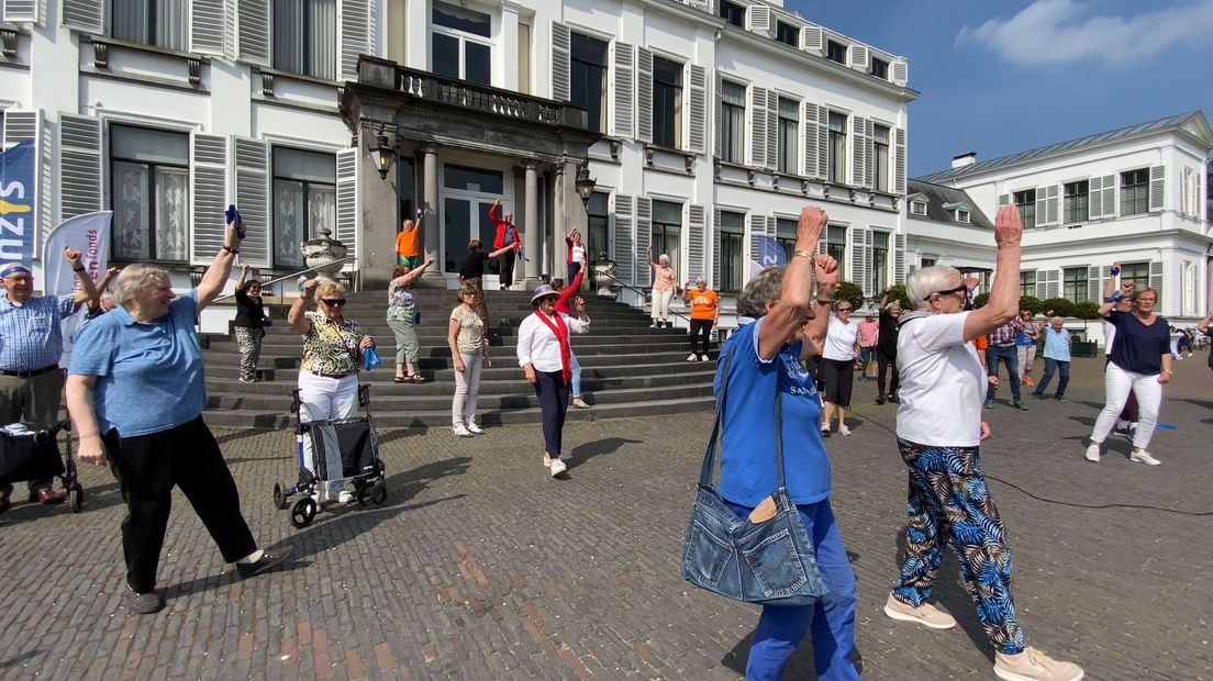 Tientallen ouderen bewegen op muziek op het bordes van Paleis Soestdijk