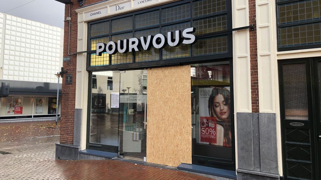 De vernielde pui van de parfumerie is gebarricadeerd met een houten schot