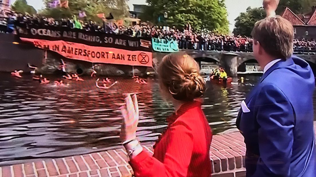 De activisten staan op de kade terwijl de Oranjes toekijken.