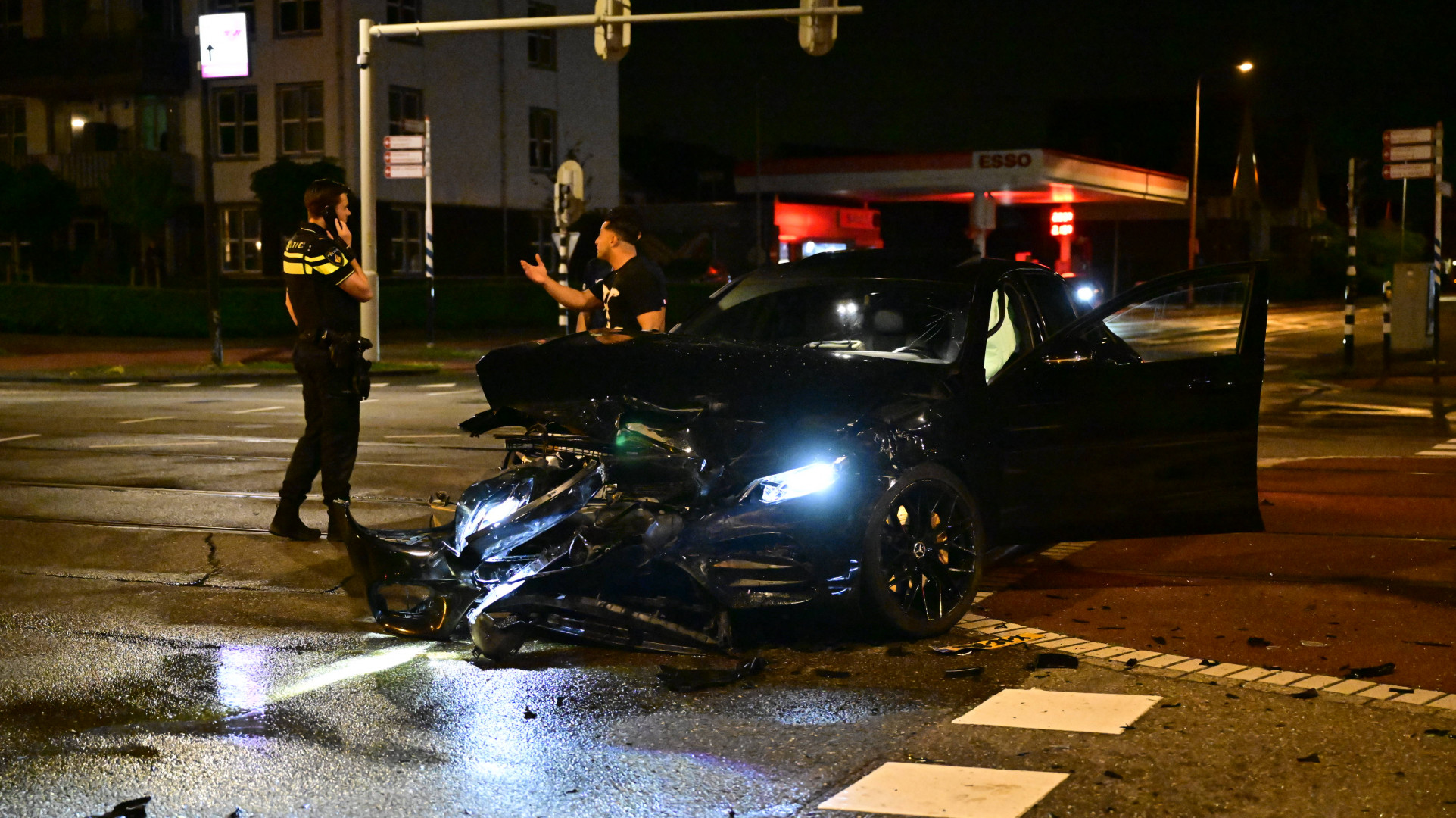 Ongeluk op kruispunt, weg bezaaid met brokstukken.