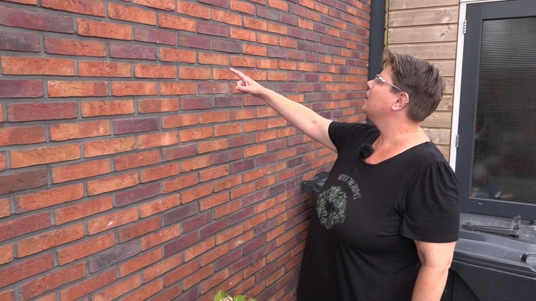 Tineke wijst naar scheuren in de muur