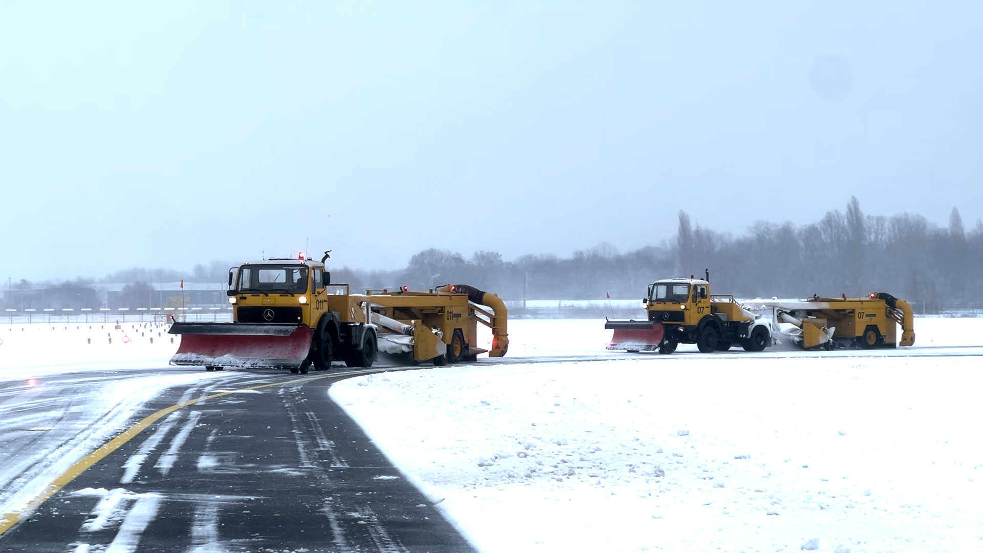 Sneeuwschuivers van de luchthavenbrandweer maken de landingsbaan sneeuwvrij.