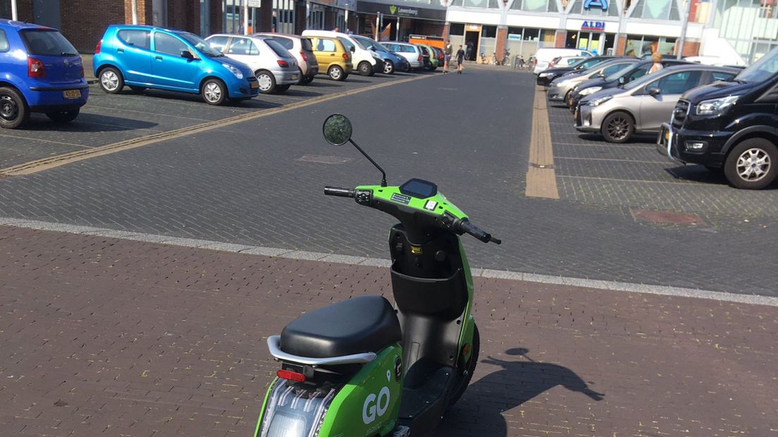 Een deelscooter geparkeerd op een uitrit van een parkeerplaats