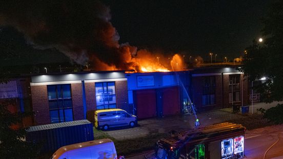 Grote brand in bedrijfspand, vlammen slaan uit dak