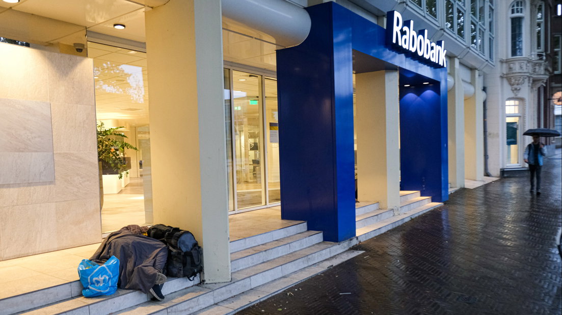 Een dakloze man slaapt op de trappen van een filiaal van de Rabobank in Den Haag