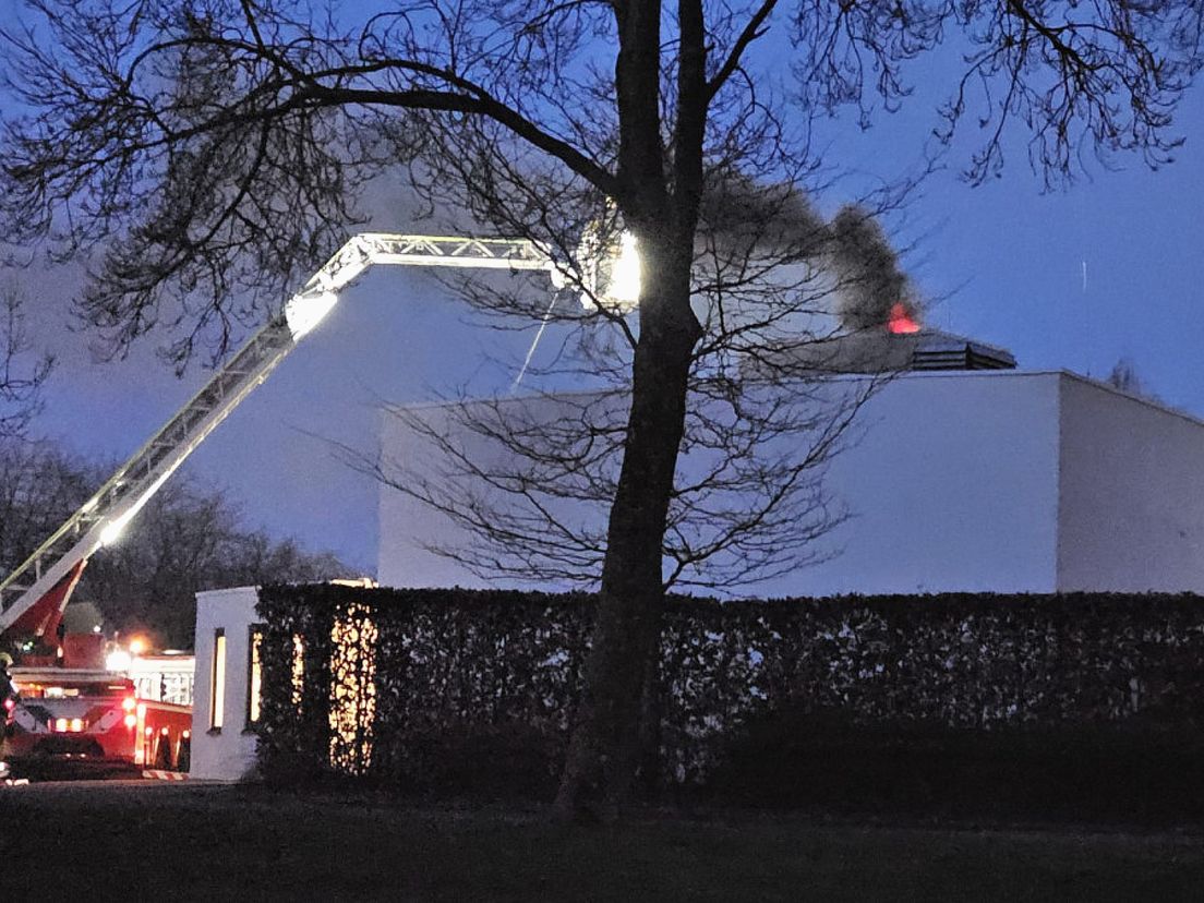 Vlammen slaan uit het dak van het crematorium in Dordrecht.