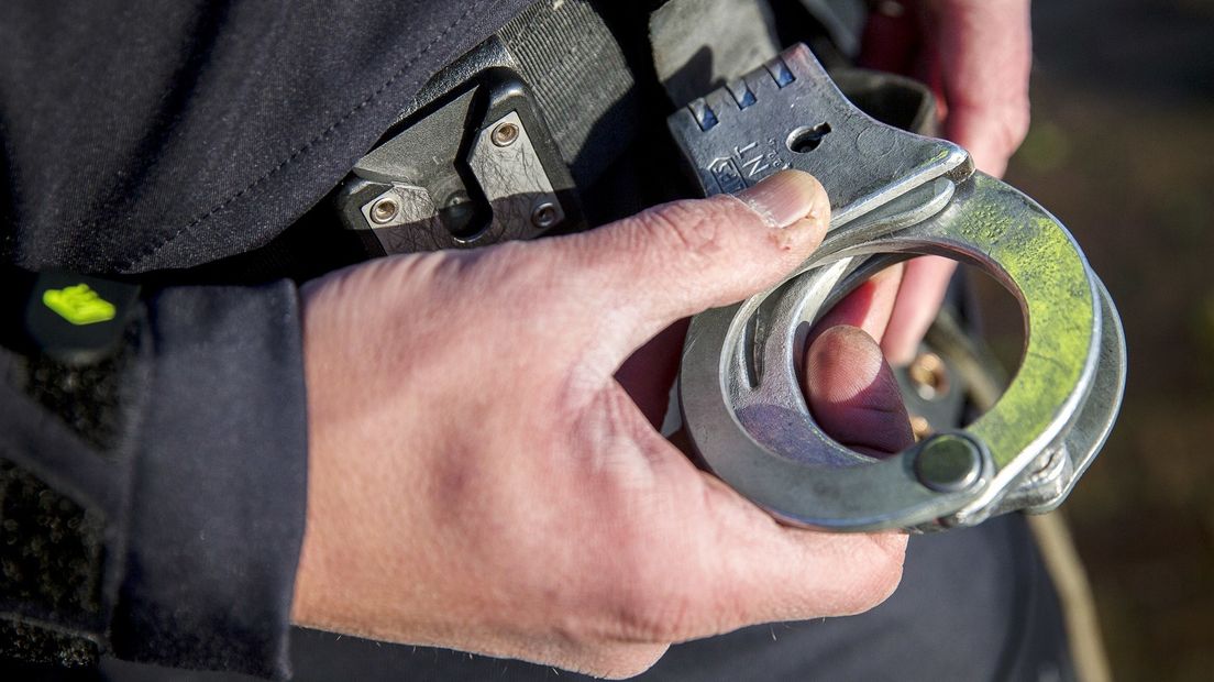 Politieagent pakt handboeien van zijn riem om een verdachte te arresteren