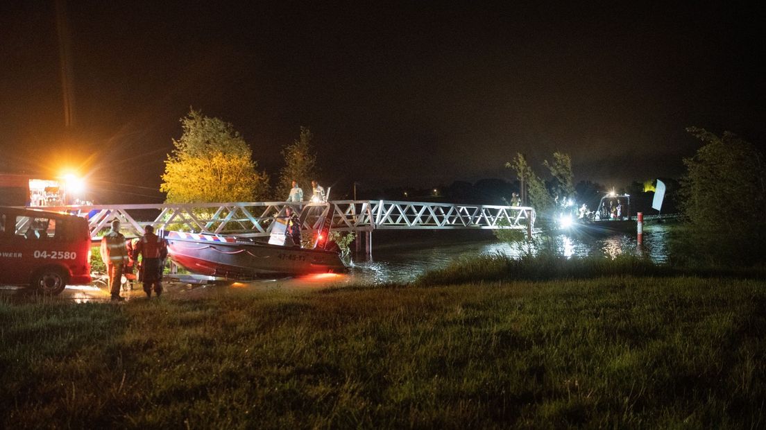 Brandweer haalt man en hond met boot van landtong langs de IJssel.