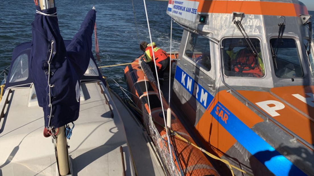 Medewerkers van de KNRM trekken de gestrande boot vlot en slepen hem naar IJmuiden