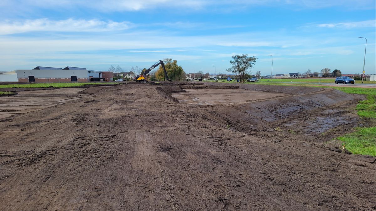 Grote berg bagger wordt gestort op weiland, komt uit sloten in omgeving