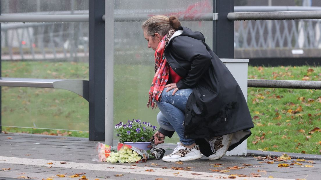 Een vrouw legt bloemen neer bij de tramhalte Anthony Fokkersingel