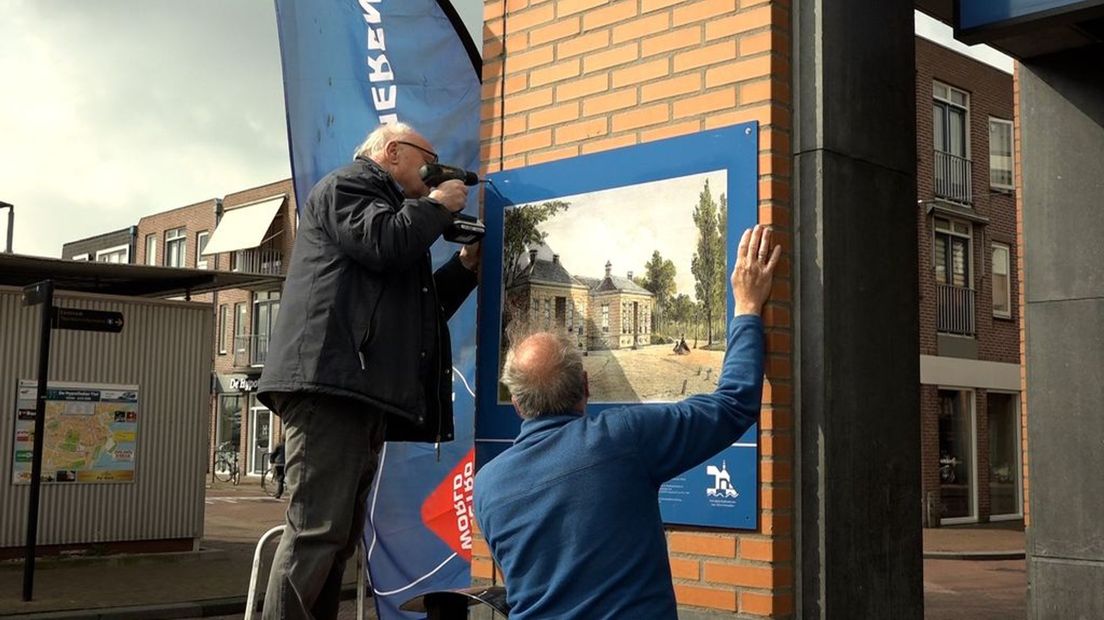 Het bord van de Zandwijkse Poort wordt bevestigd.