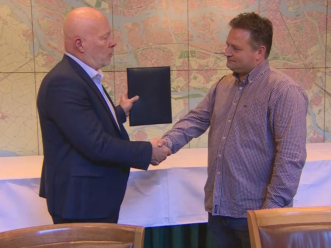 Wethouder Robert Simons (Leefbaar) en Yoek Kouwenhoven namens het Recreatieoord Hoek van Holland schudden elkaar de hand na het ondertekenen van de overdracht