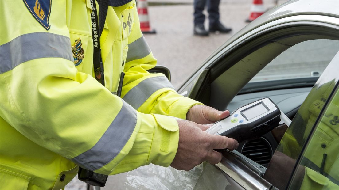 Een politieagent neemt een blaastest af tijdens een controle actie.