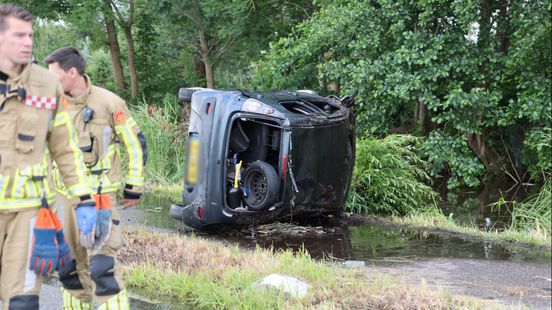 Auto slaat over de kop bij ongeluk, duikers zoeken in water Home