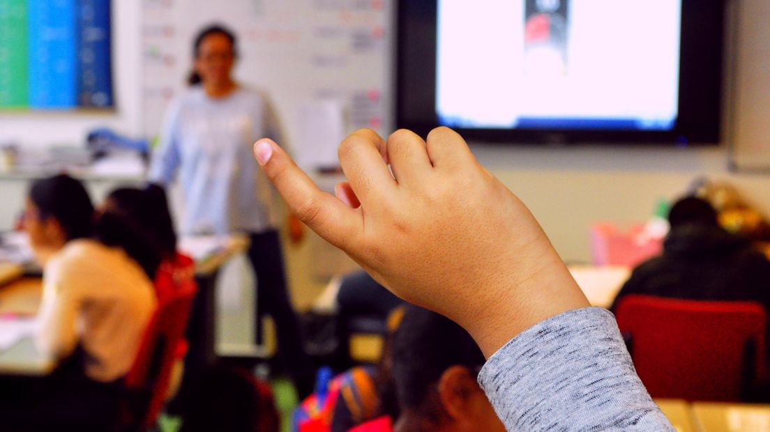 Een leerling steekt zijn vinger op in de klas