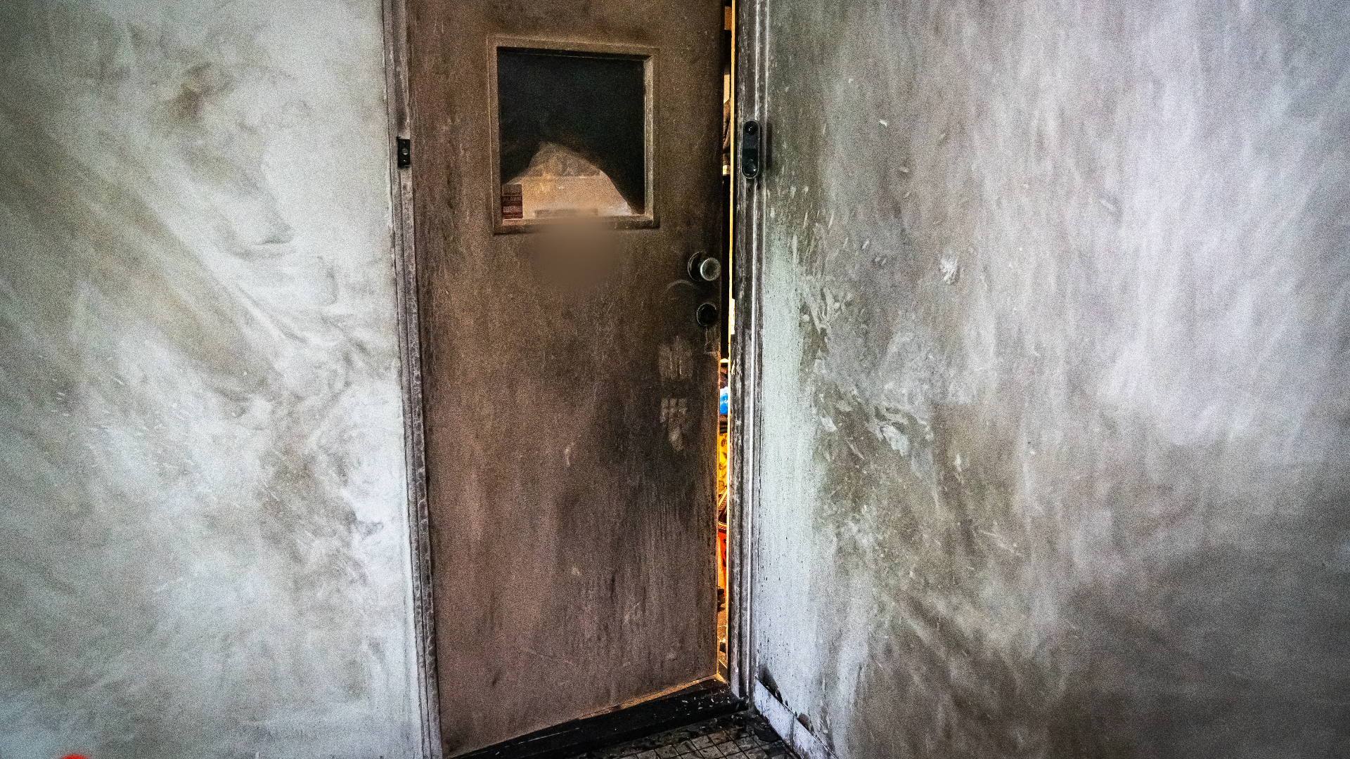 Zwartgeblakerde muren en schade aan de voordeur na de explosie.