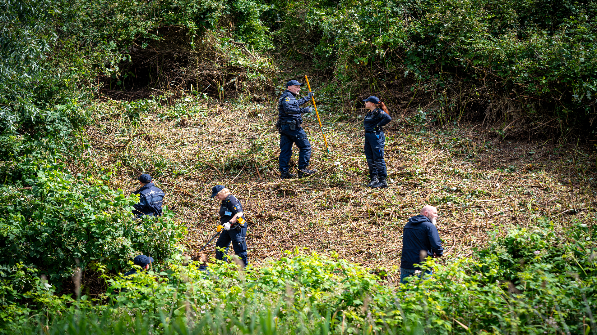 Een deel van de berm is gekapt, met metaaldetectoren wordt gezocht door agenten.