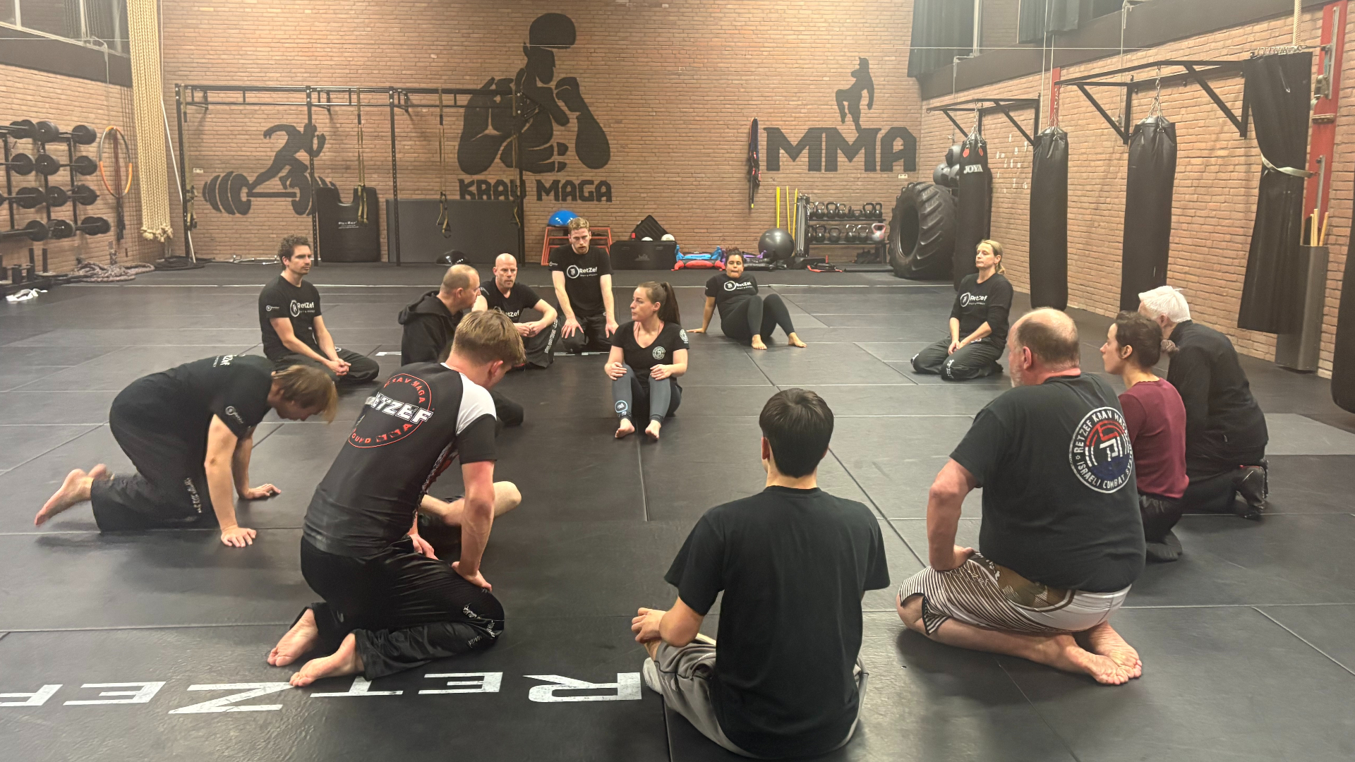 De groep zit op de grond bij krav maga