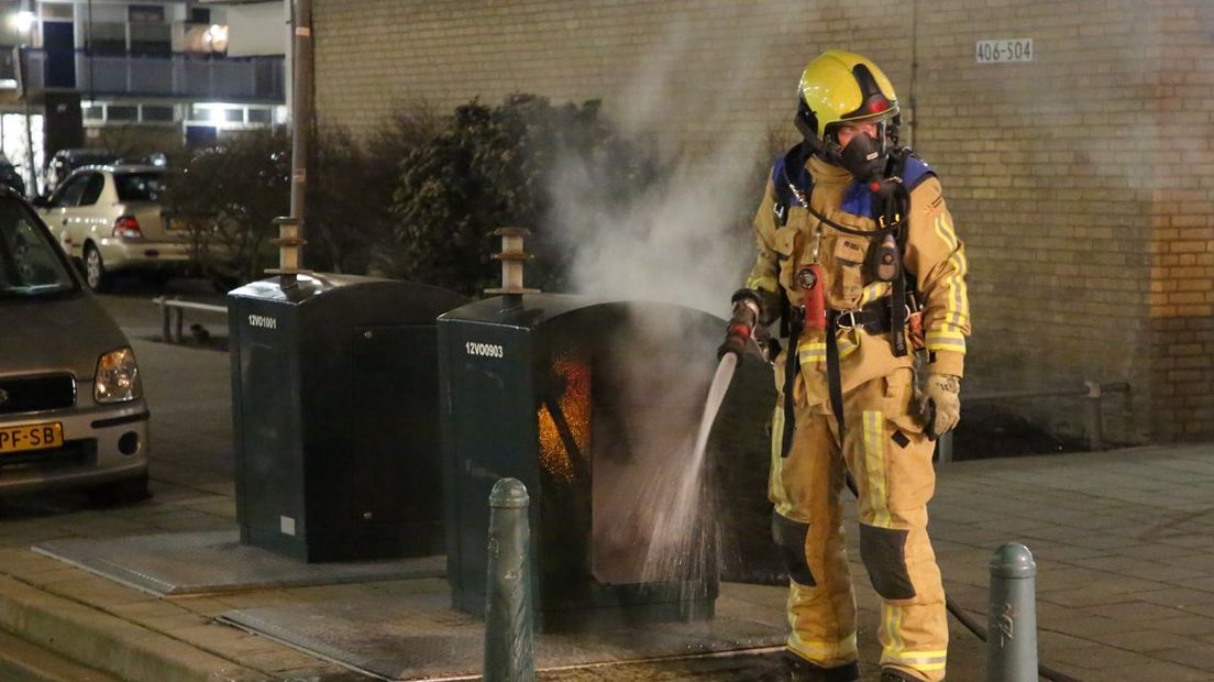 De brandweer blust de containerbrand