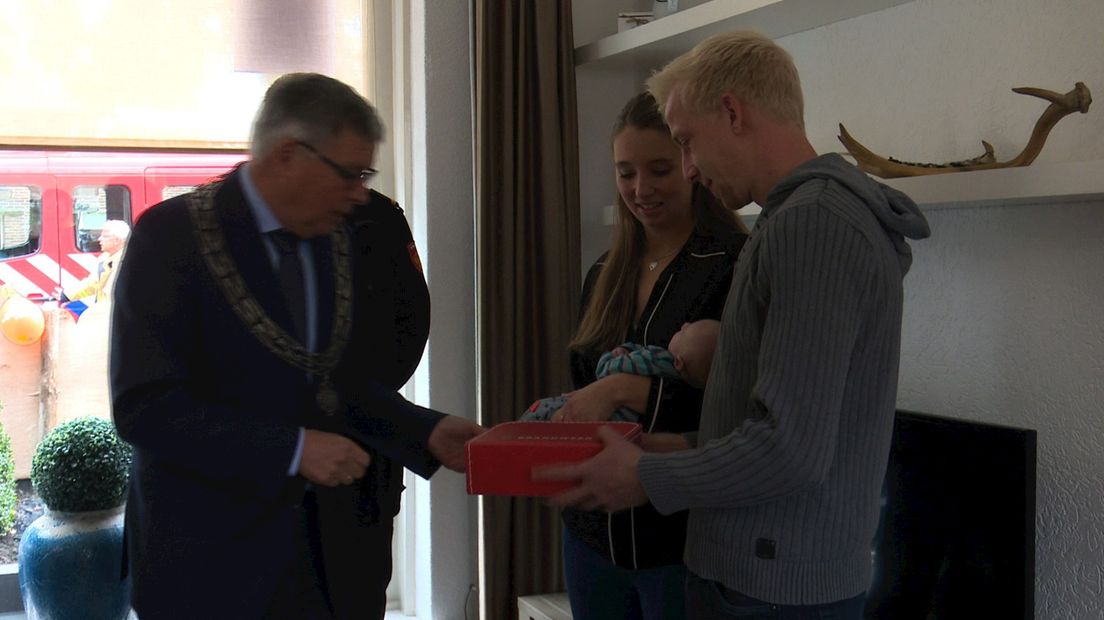 Burgemeester Robben reikt het geboortekoffertje uit.