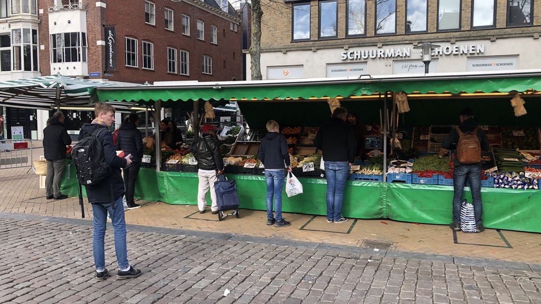 Mensen houden afstand bij een marktkraam op de Vismarkt