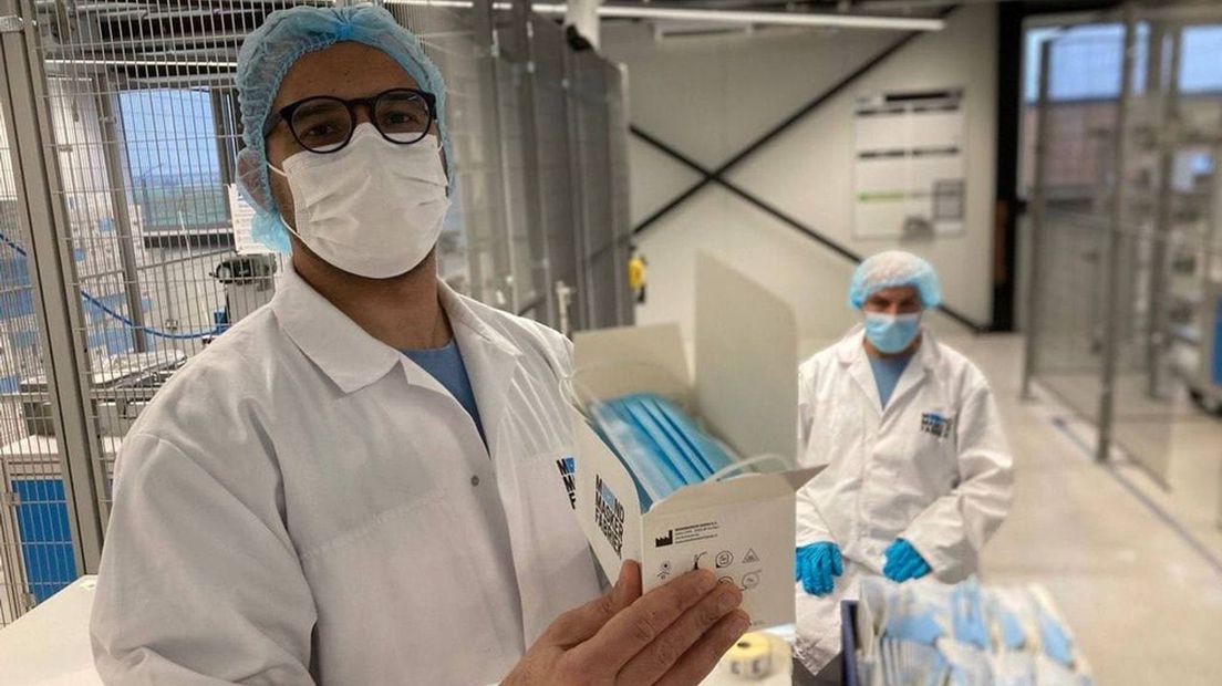 Een voorman in de fabriek toont de mondkapjes die momenteel worden gemaakt.