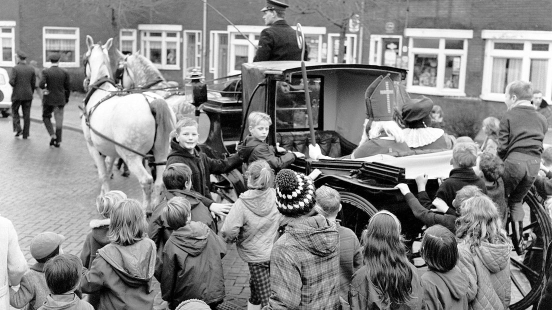 1965: Sinterklaas en Zwarte Piet maken een rondrit door Zuilen. Een groep schoolkinderen in de Adriaan van Bergenstraat volgt de koets van de goedheiligman.