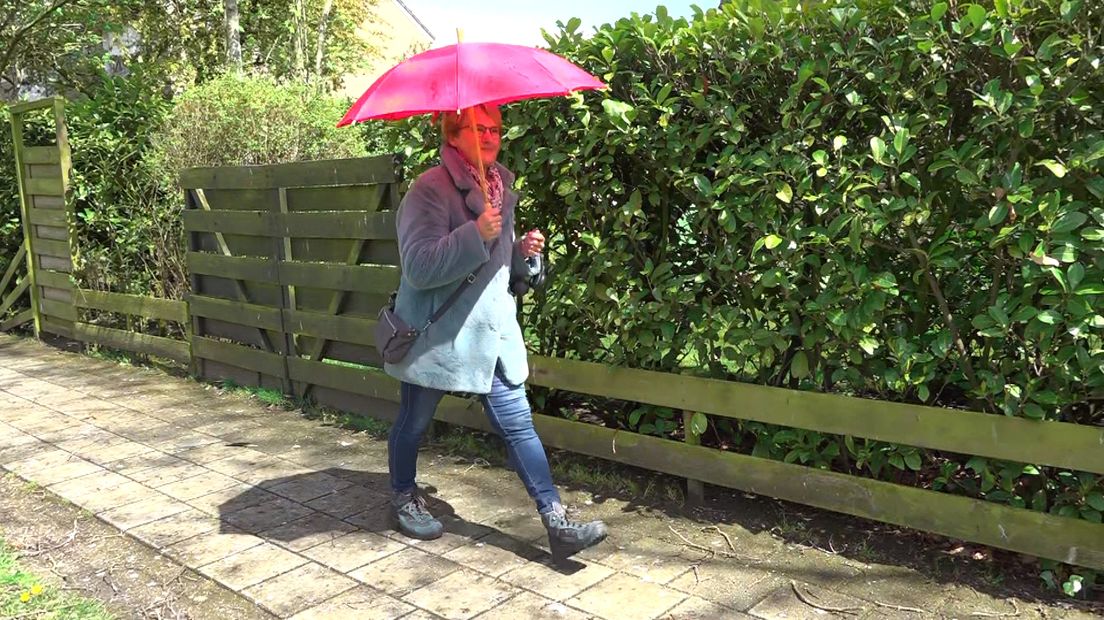 Ria Weerd loopt met paraplu op door de straten van Leek