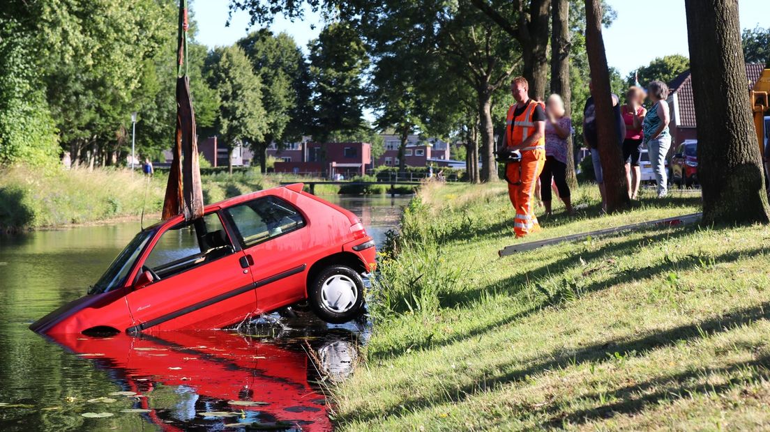 Een rode auto is zondagmiddag het water ingerold in Veendam