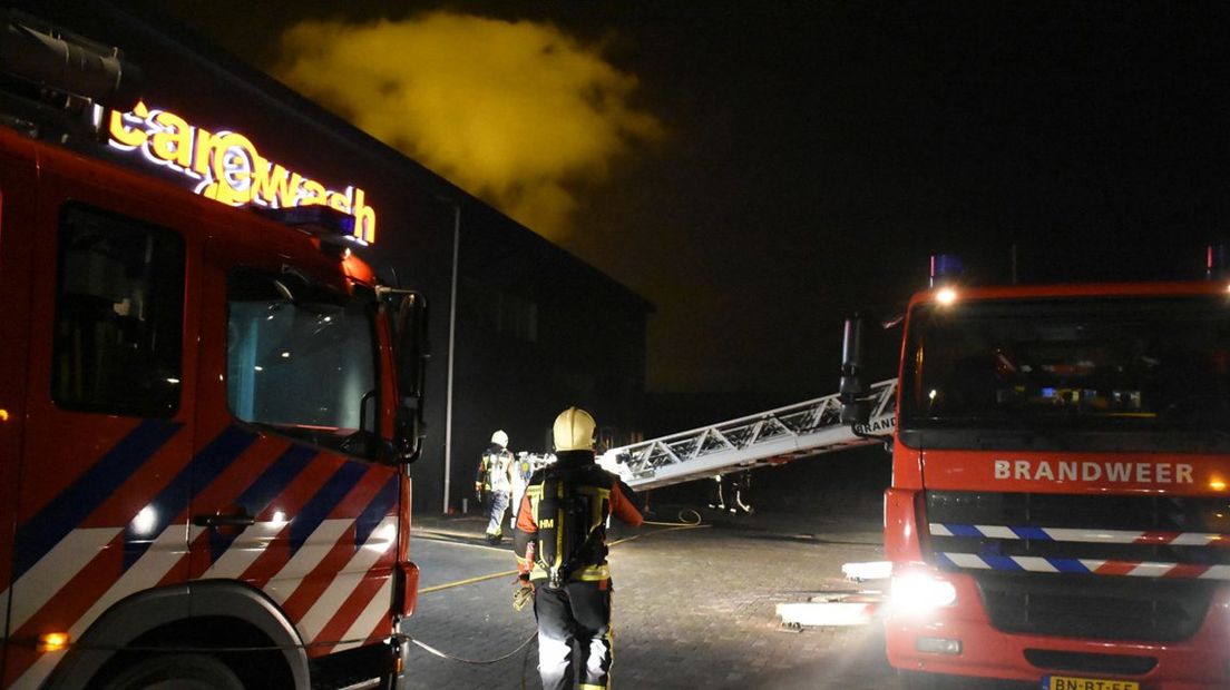 De brandweer blust de brand bij de autowasstraat