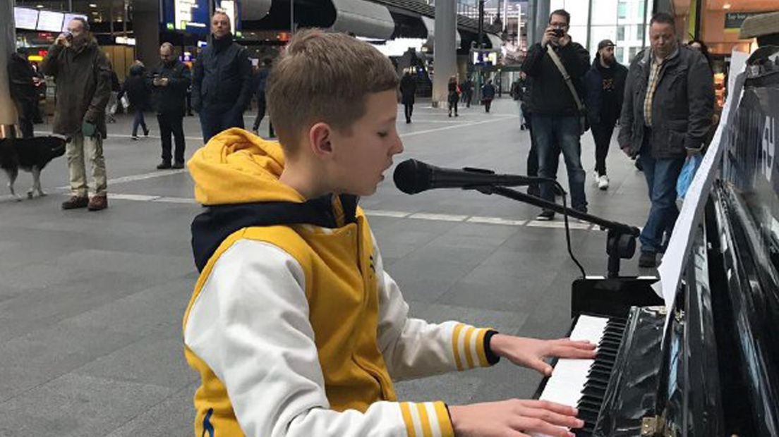 Bas Schipper achter de piano in Den Haag, één van de 16 stationspiano's die hij vandaag bespeelt.