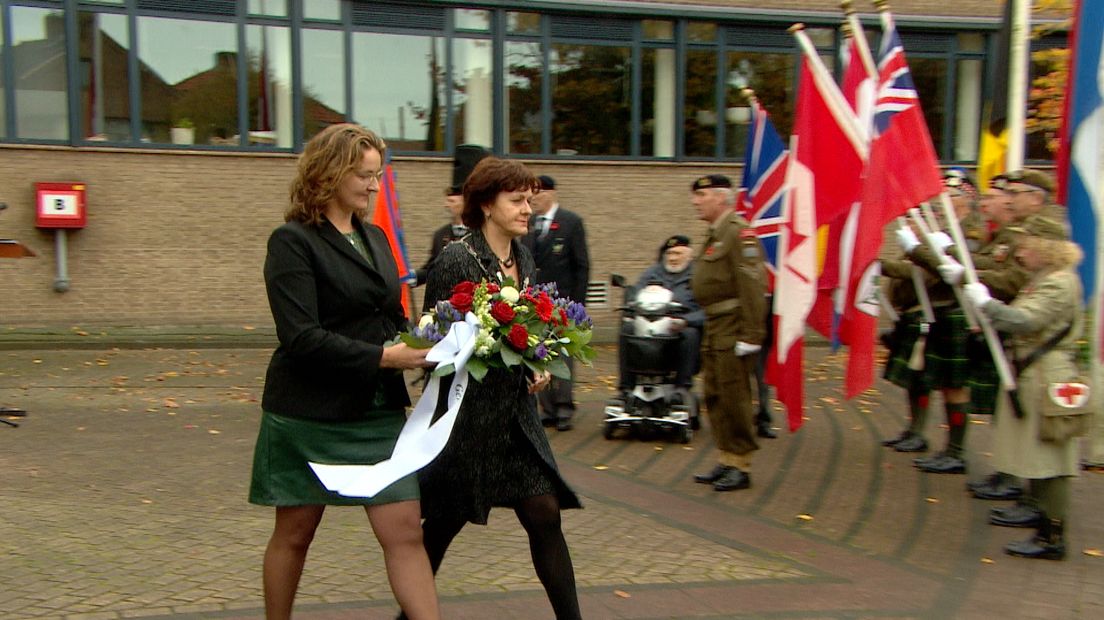Wethouder Marianne Poissonnier en burgemeester Marga Vermue van Sluis leggen bloemen bij het oorlogsmonument in Oostburg.