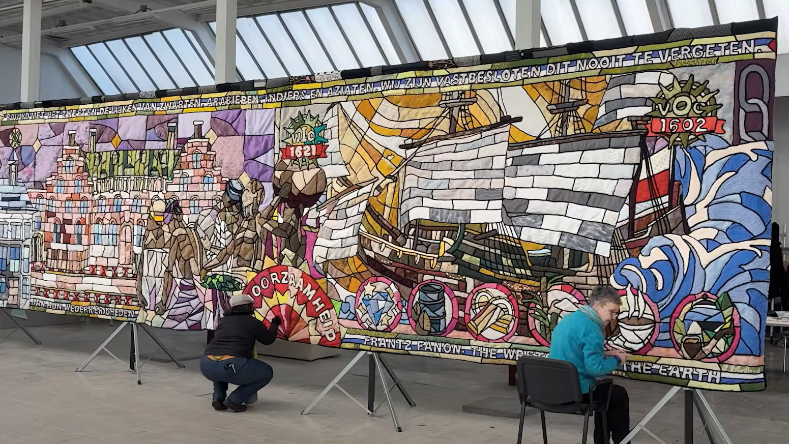 Vrijwilligers werken aan het grote wandkleed