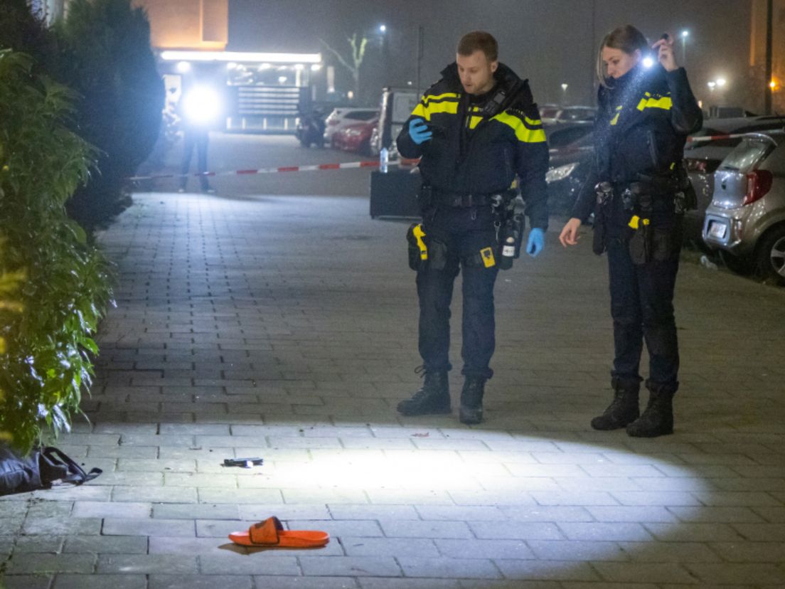 De politie doet onderzoek bij de flat waar Dennis zijn moeder aanviel. Op straat ligt zijn slipper.