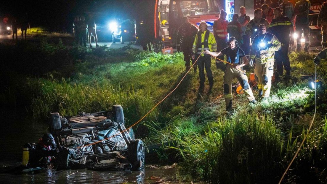 Duikers van de brandweer gaan op zoek naar eventuele inzittenden, nadat een auto op de kop in de sloot was beland.