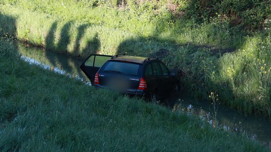 Auto met lege wijnflessen in water in Vlaardingen