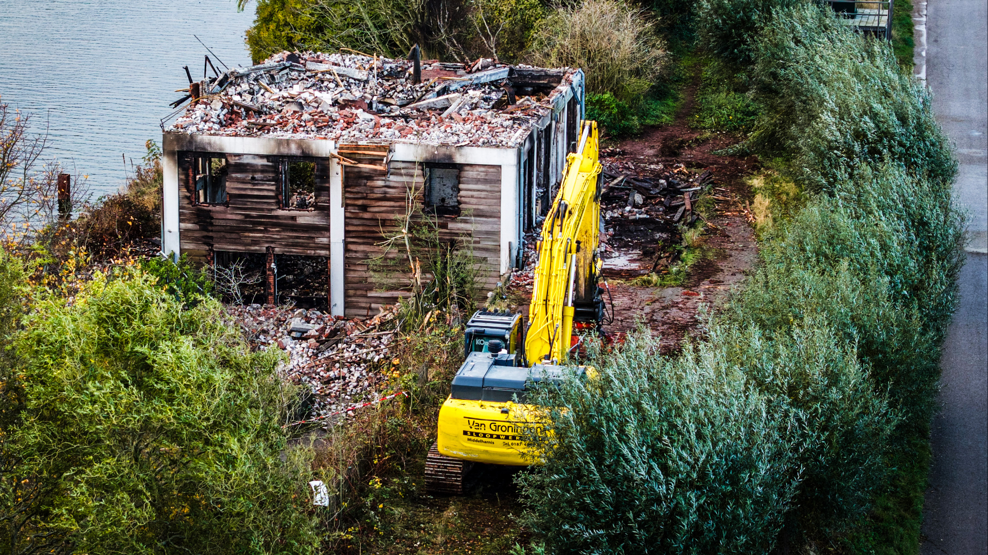 Een kraan is bezig om delen van het pand te slopen nadat het door brand is verwoest