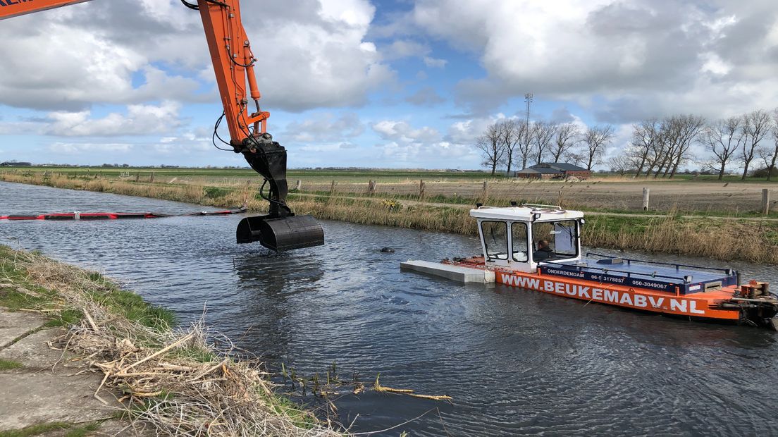 De duwboot schuift het slib naar de graafmachine