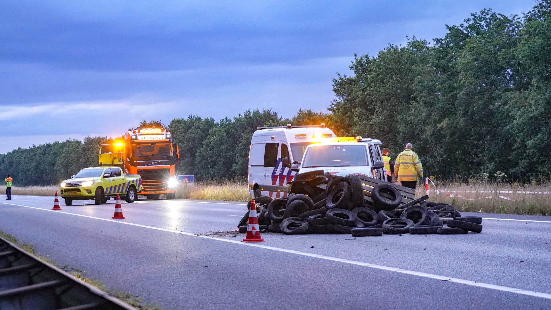 Politie en Rijkswaterstaat bij een berg gedumpte autobanden ter hoogte van Leek