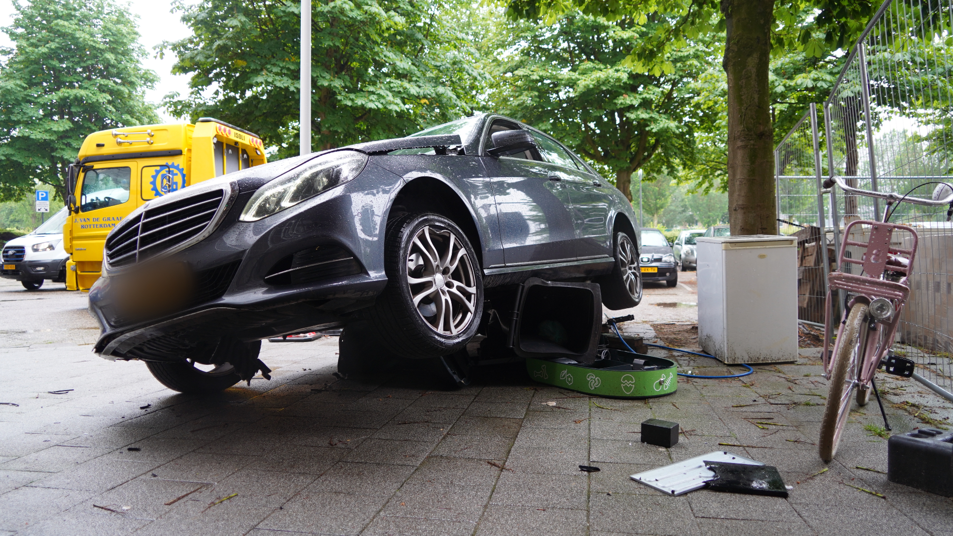 De auto reed een pullenbak omver voor de ingang van het appartementencomplex.