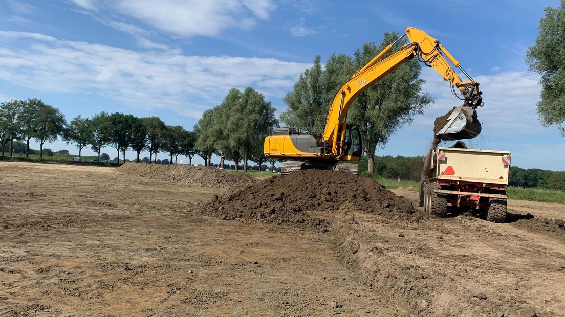 Tientallen tractoren rijden op en neer met het afgegraven zand