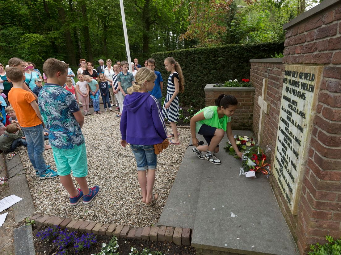 Kinderen leggen een krans bij het monument