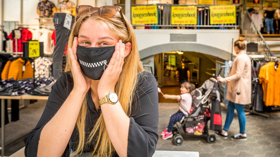 Een vrouw draagt in een winkel een mondkapje