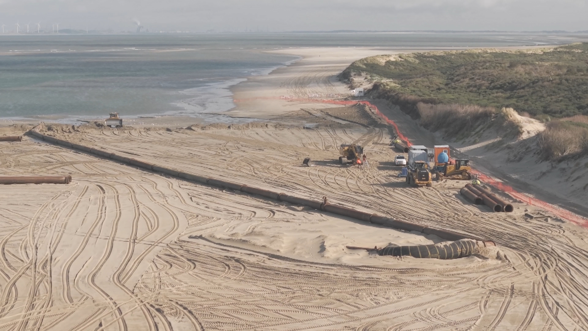 Een grote pijpleiding spuugt het zand op het strand