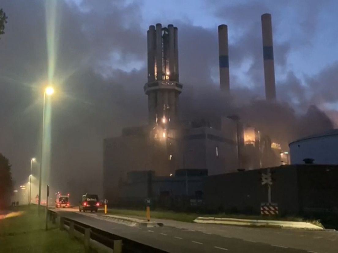 De rook van de brand waait over de weg.