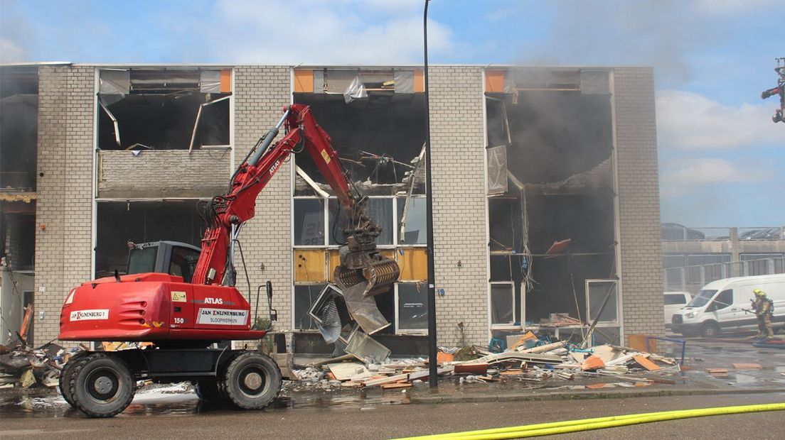 De brandweer sloopt delen van het pand om de brand te bestrijden